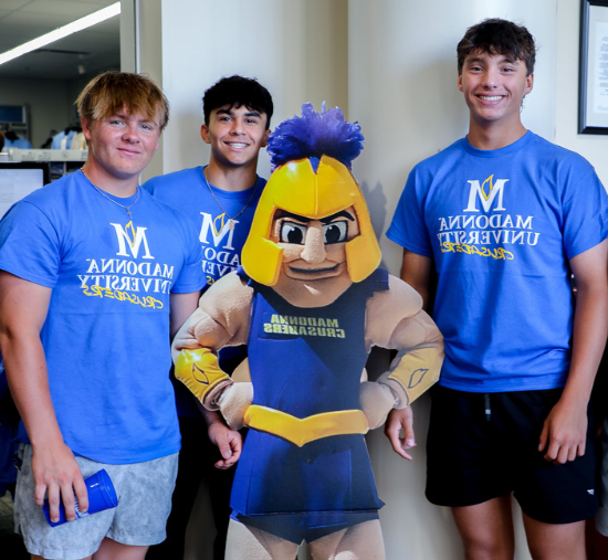 3 male students smiling next to cardboard cutout of cruzer