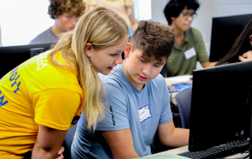 peer mentor assisting prospective student on the computer during orientation